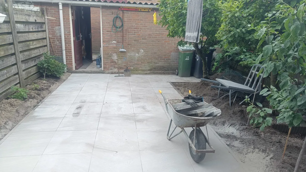 Achtertuin net betegeld, kruiwagen nog in de tuin