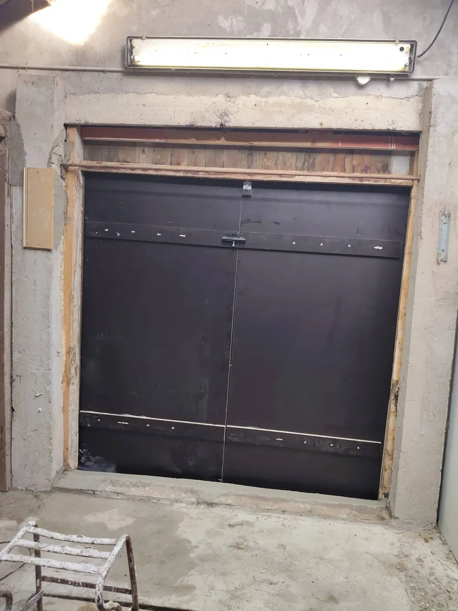 Dezelfde wand na de klus, met twee zwarte deuren tot op de vloer