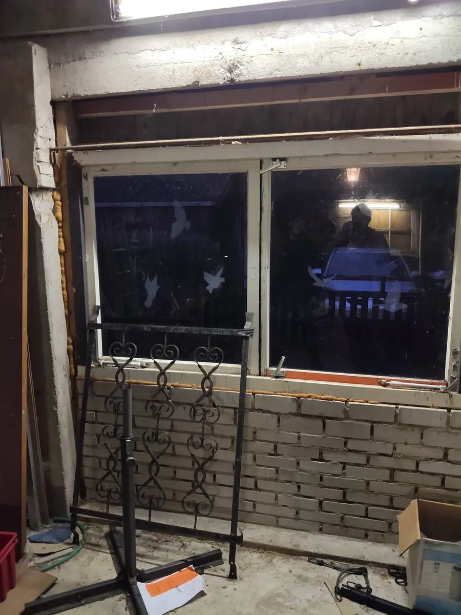 De garagewand voor de klus, met een oud raam boven een muurtje