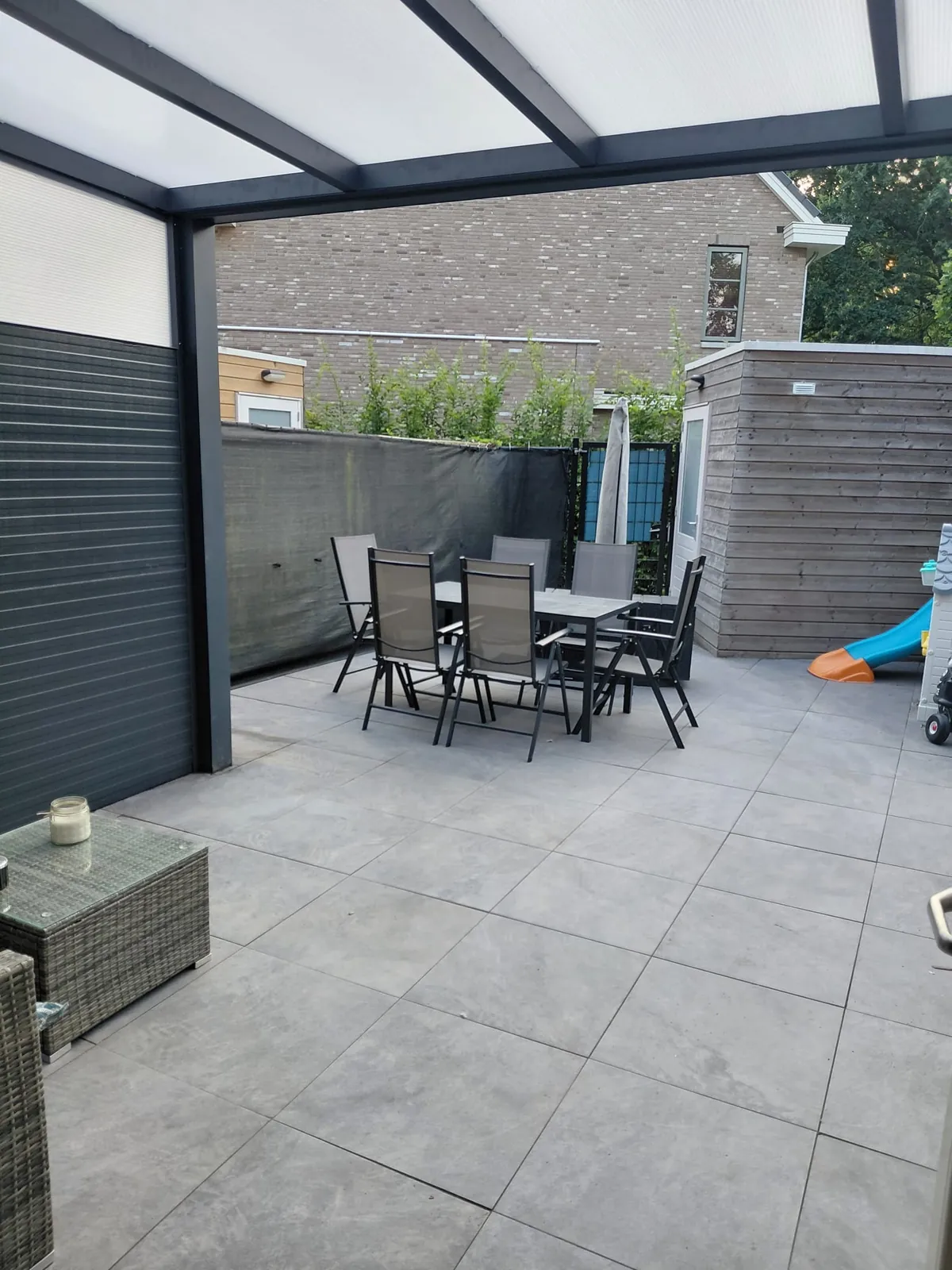 Terras met grote tegels onder een aluminium overkapping, door Lucas gemaakt